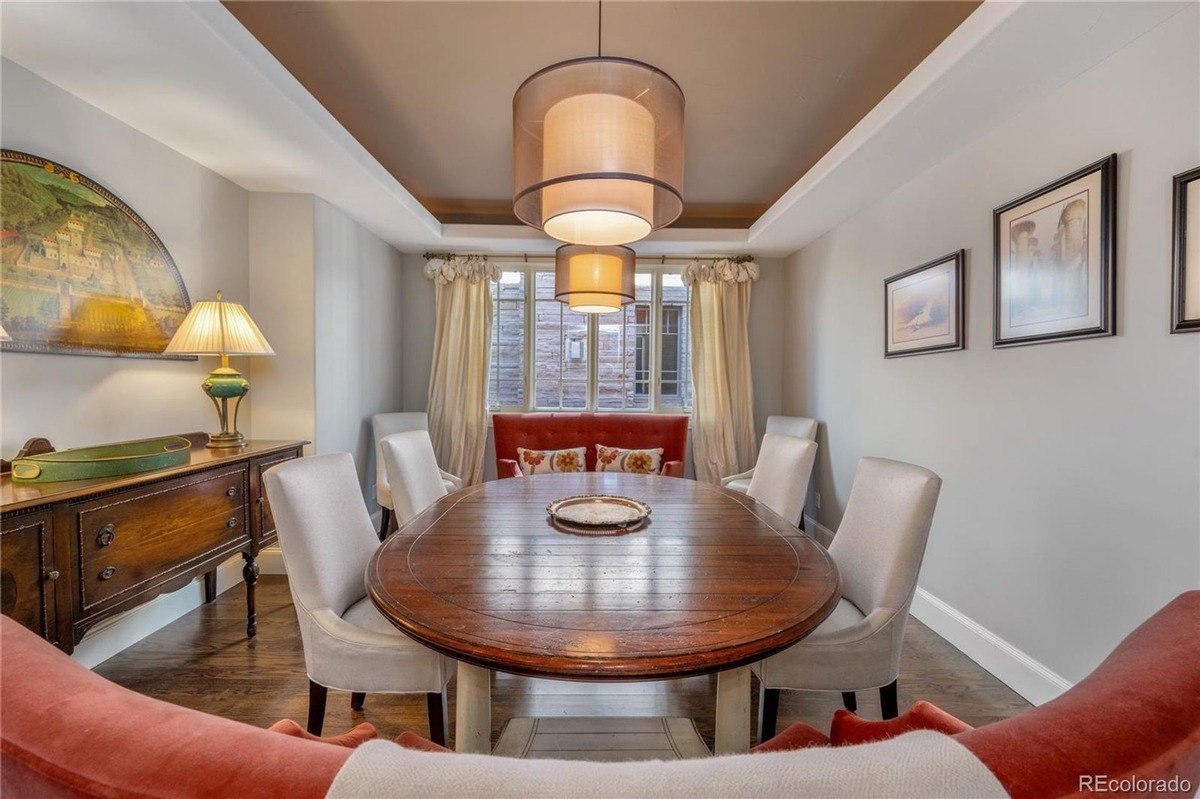 Dining room with wood table and chairs, chandelier, and artwork on walls.