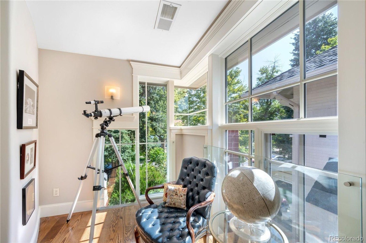 Room has large windows, telescope, globe, and leather chair.