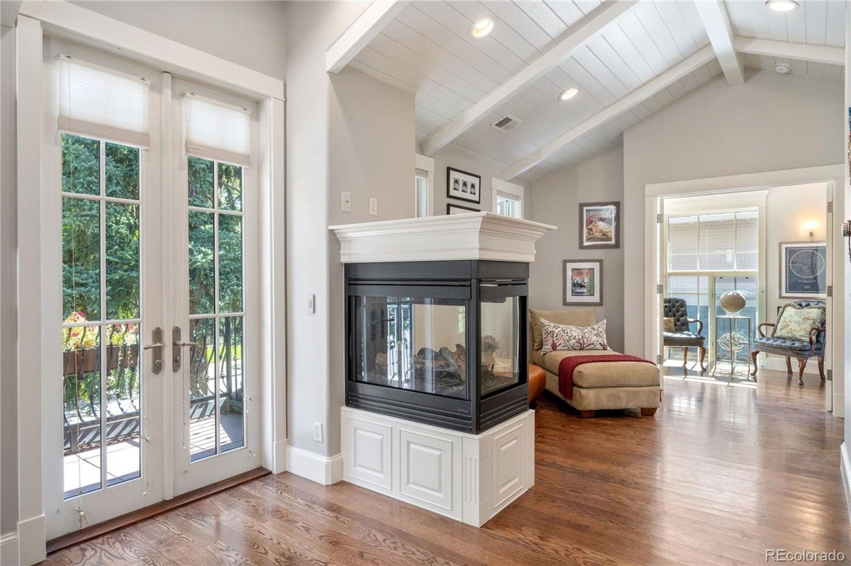 Room has hardwood floors, vaulted ceiling, fireplace, and French doors.