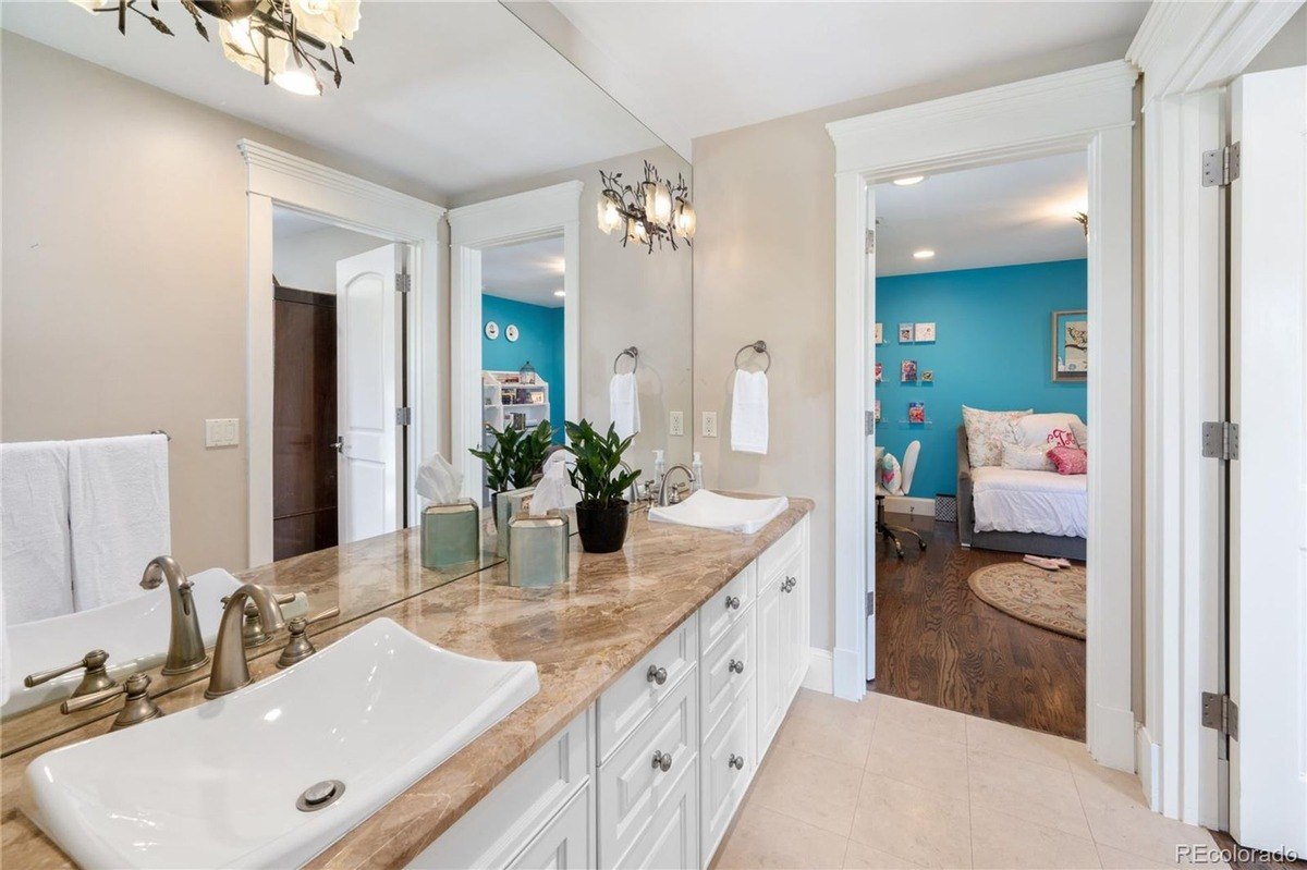 Bathroom has double vanity with granite countertop, sink, and view of child's bedroom.