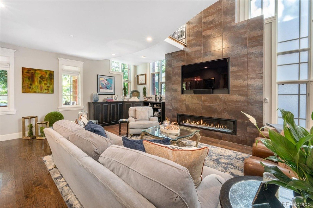 Living room with large sectional sofa, fireplace with TV above, and hardwood floors.