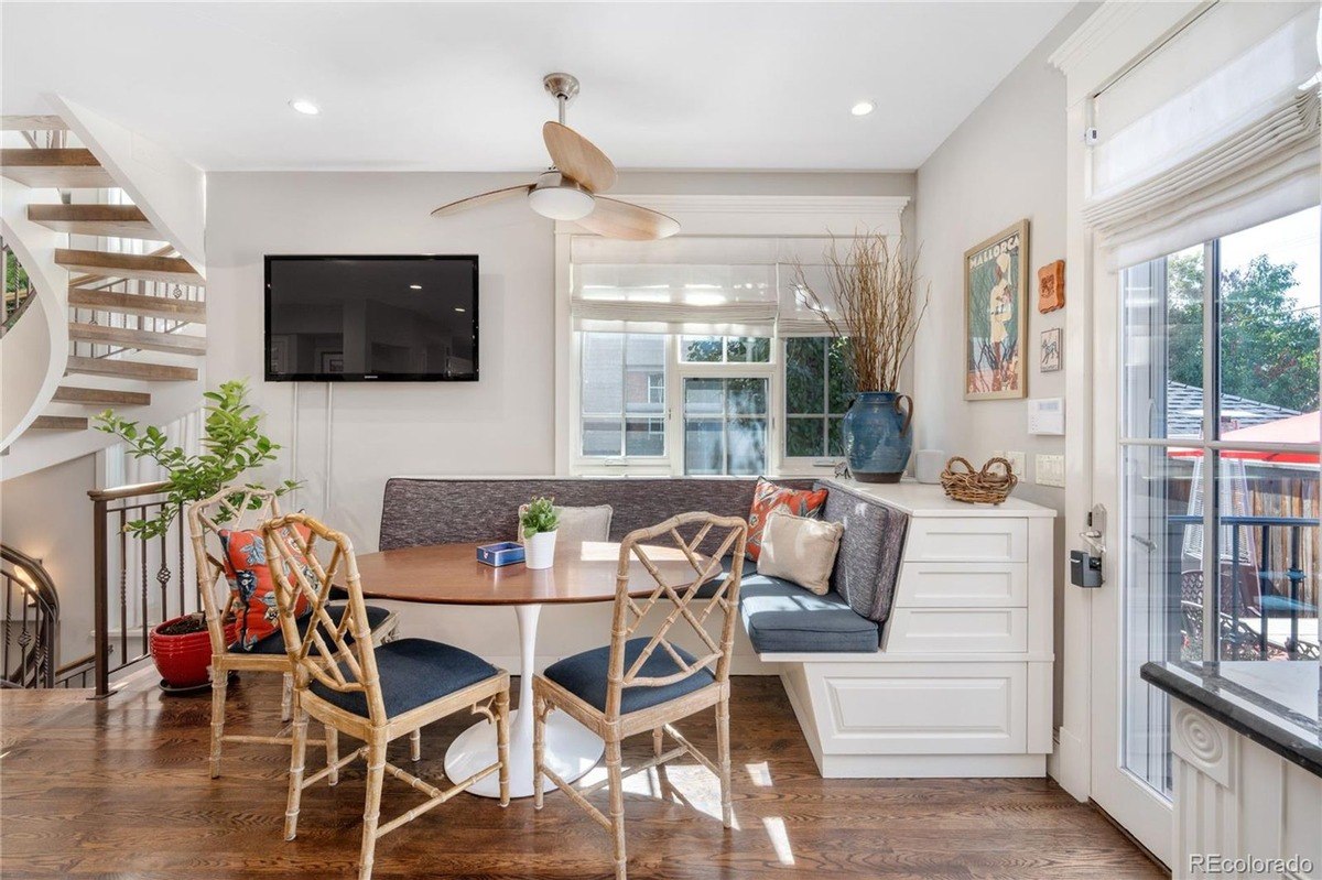 Breakfast nook with built-in banquette seating, table with chairs, and ceiling fan.