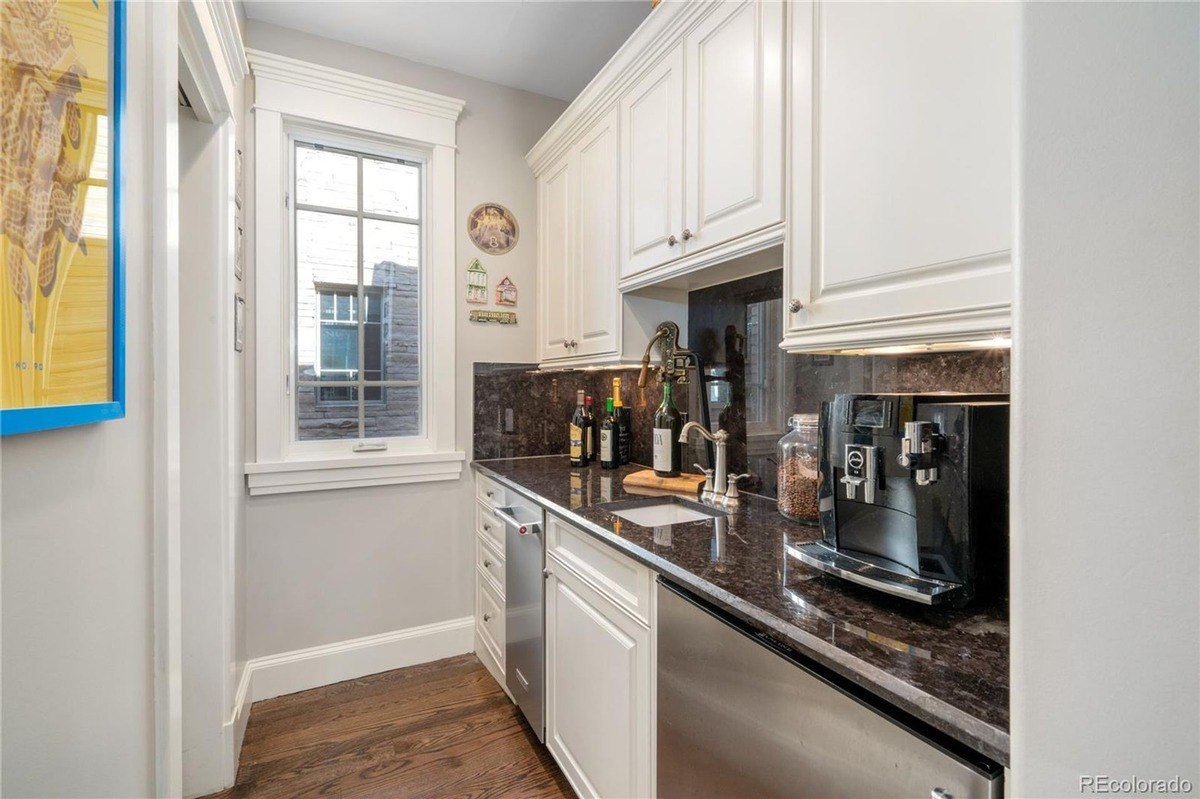 Butler's pantry has white cabinets, granite countertops, and espresso machine.