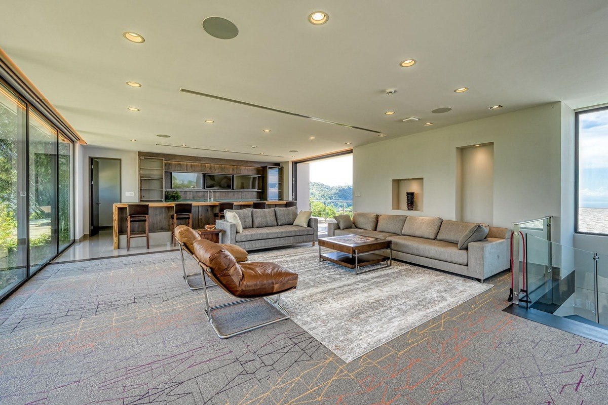 Living room has gray sectional sofa, brown leather chairs, and mountain view.