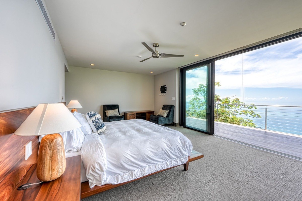 Master bedroom has king-size bed, ocean view, and ceiling fan.