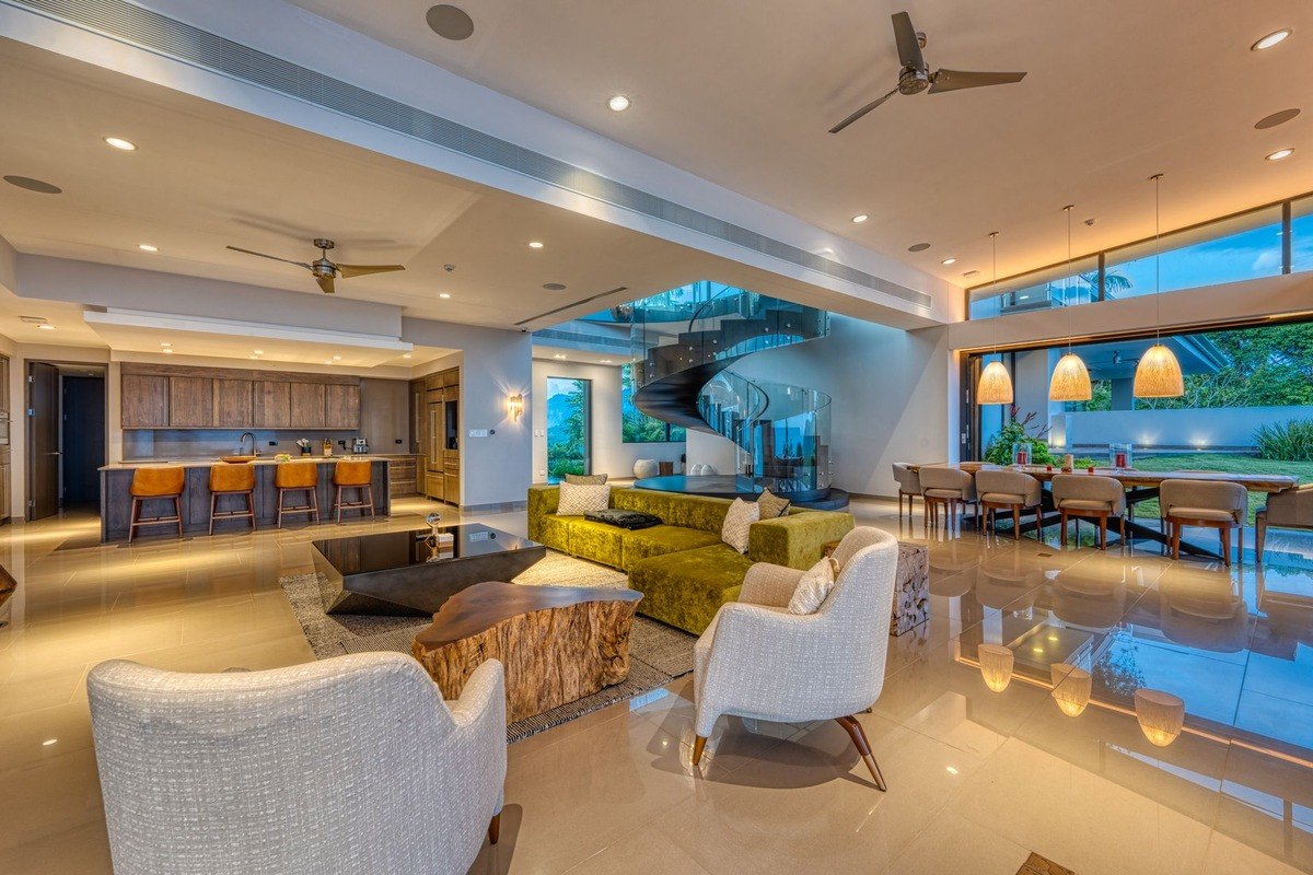 Living room has large green sectional sofa, fireplace, and kitchen view.