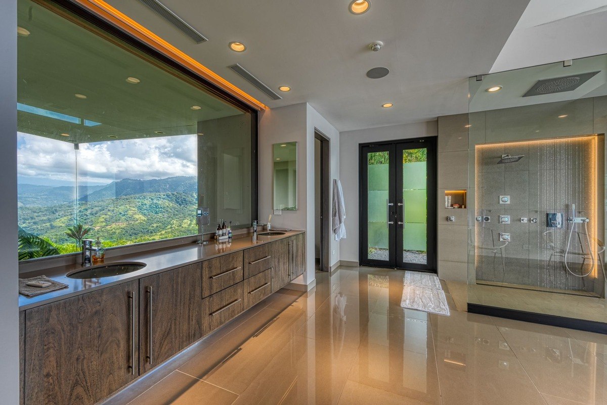 Bathroom has large window with mountain view, double sinks, and walk-in shower.