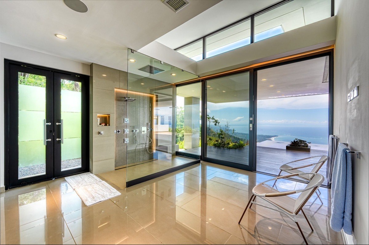 Bathroom has large glass shower, ocean view, and modern design.