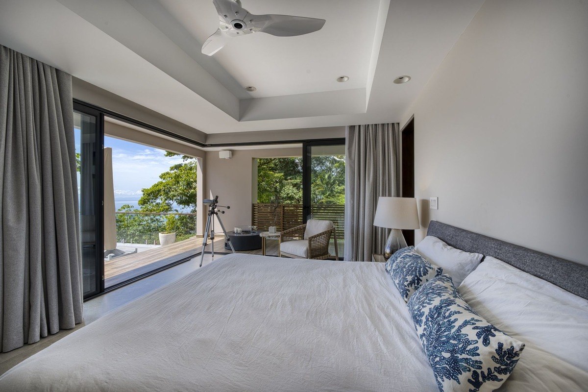 Bedroom has king-size bed, ocean view, and ceiling fan.