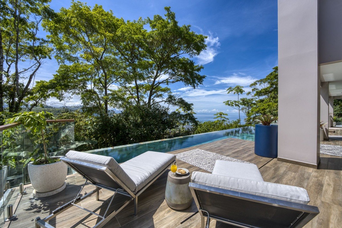 Patio has lounge chairs and infinity pool with ocean view.