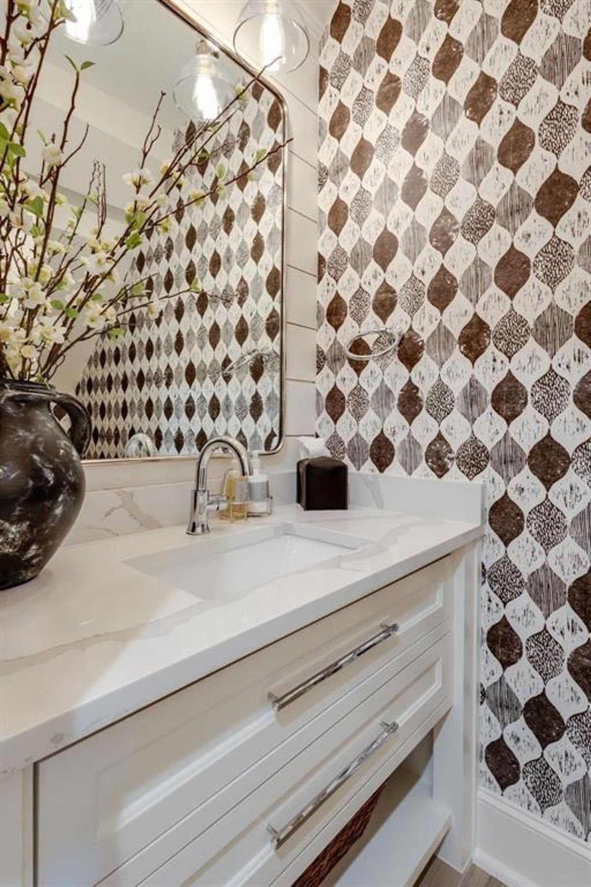 Powder room design highlights a striking patterned wallpaper paired with a white countertop and minimalist decor.