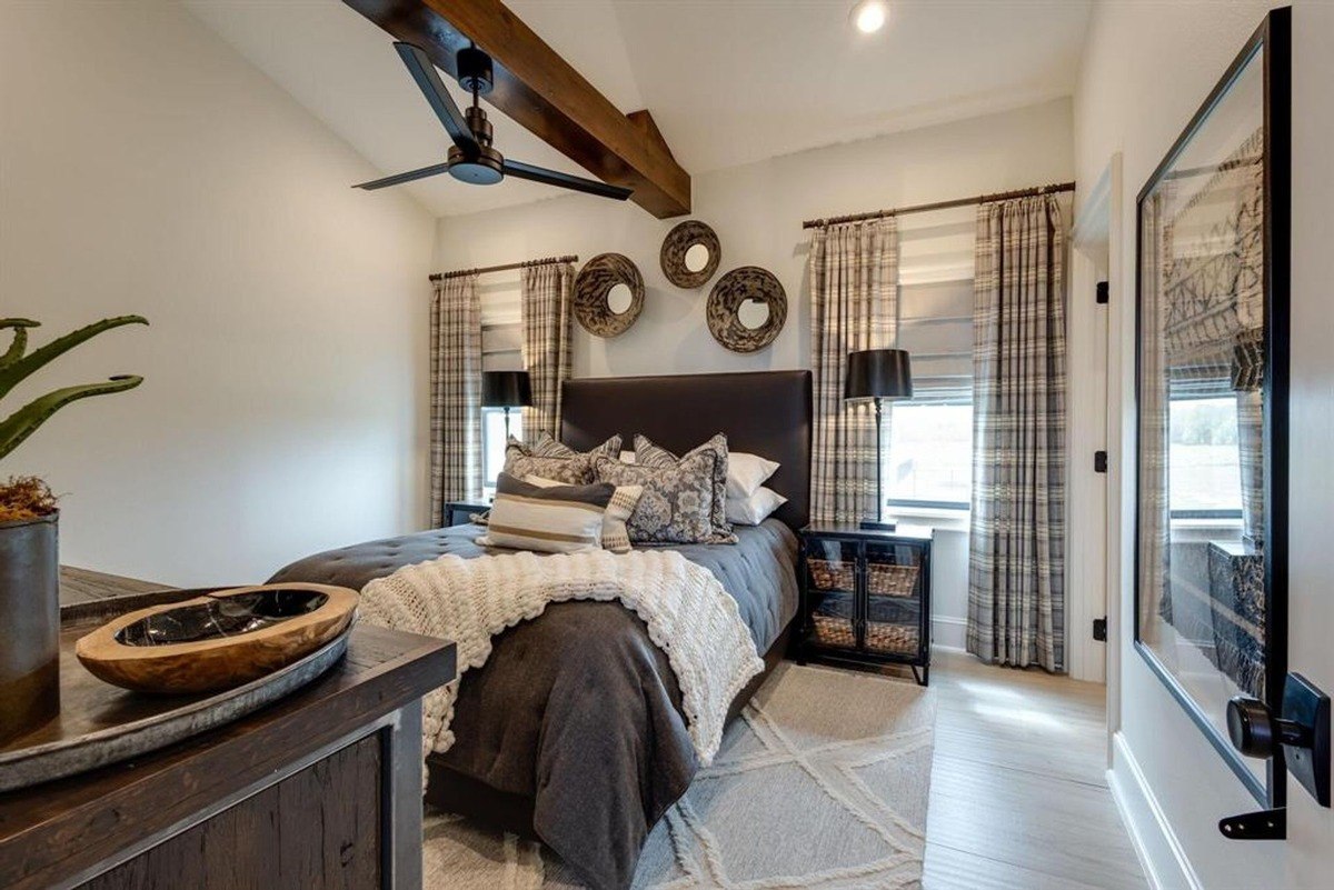 Cozy bedroom styled with plaid curtains, layered bedding, and decorative mirrors arranged above the headboard.