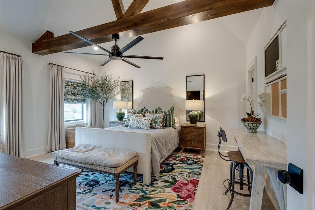 Bedroom with exposed wooden beams, a ceiling fan, and floral decor accents.