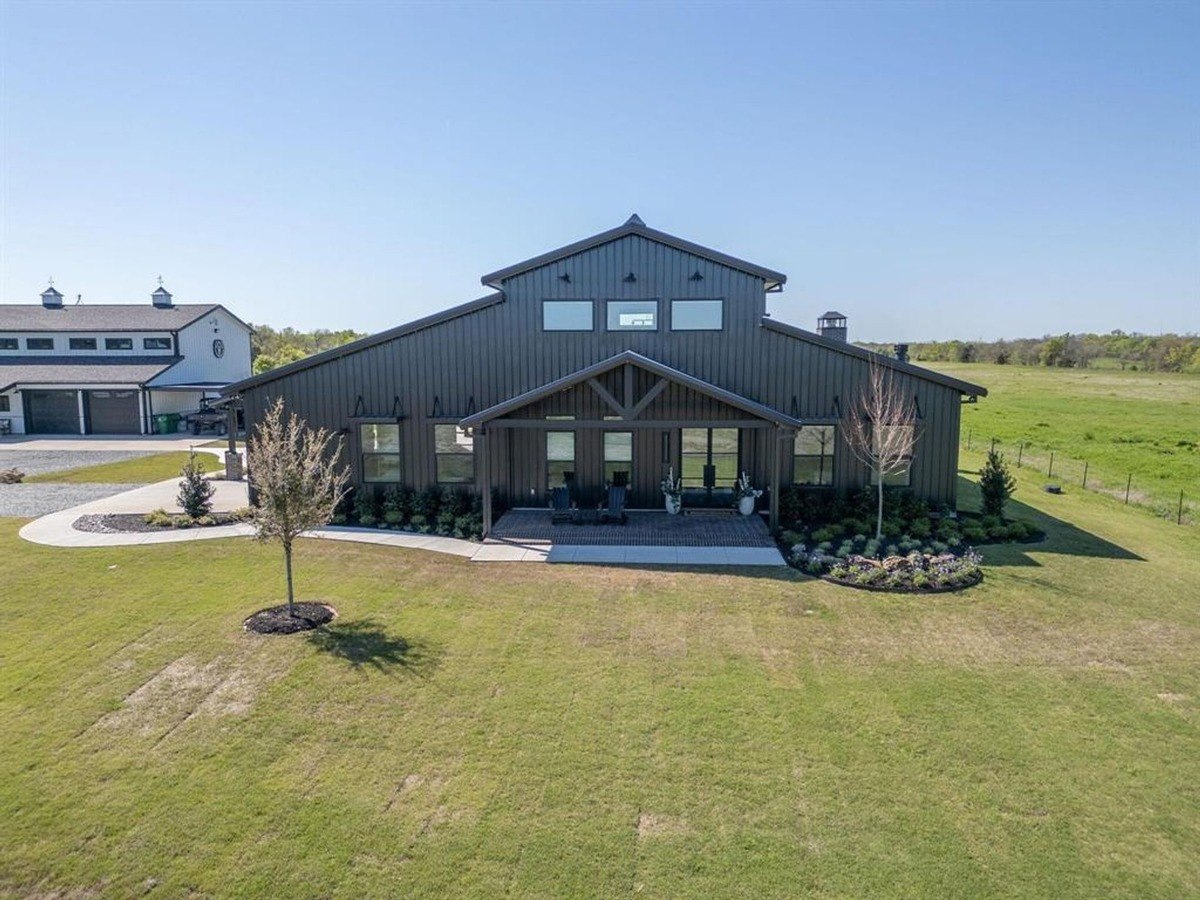 Exterior view of a barn-style structure with a landscaped lawn and paved walkway.