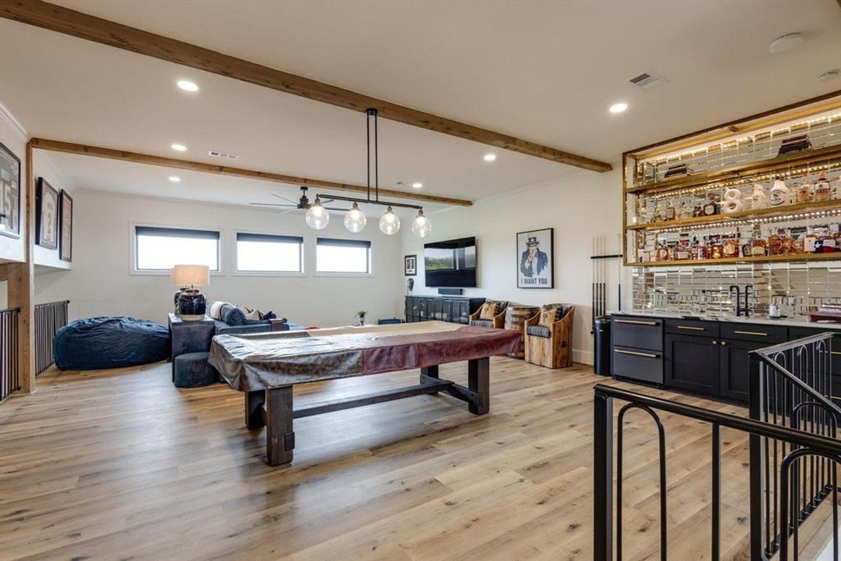 Game room with exposed wooden beams, a billiards table, and an illuminated bar area.