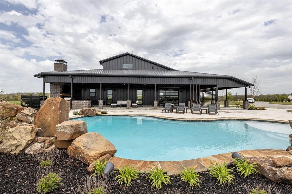 Backyard oasis showcasing a serene pool surrounded by natural stones and a covered patio.