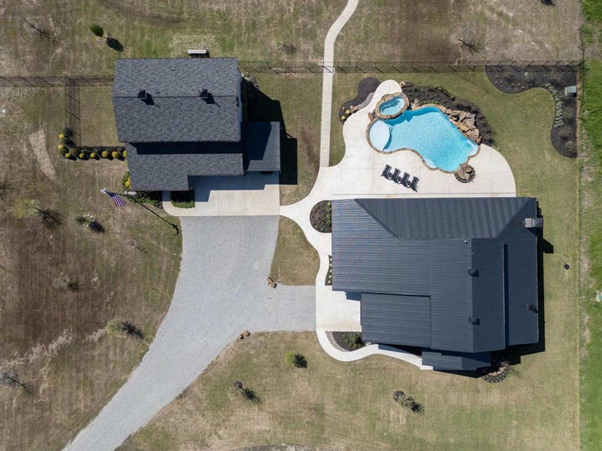 Aerial view of the property layout highlighting the main house, guest house, driveway, and pool with landscaped details.