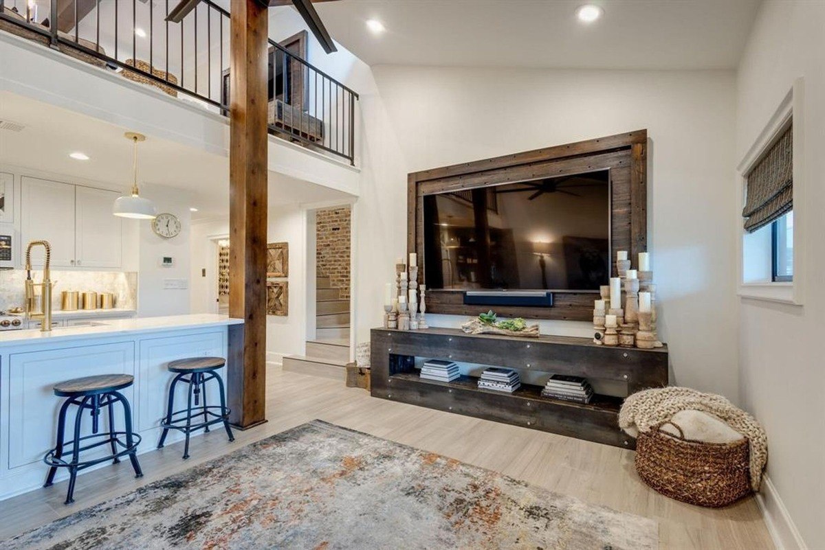 Cozy living area featuring rustic beams, a leather sectional, and an open-concept kitchen with bar seating.