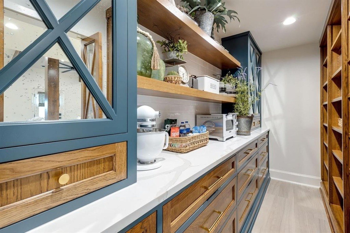 Built-in cabinetry with a navy and wood finish complements open shelving decorated with rustic accents and appliances.