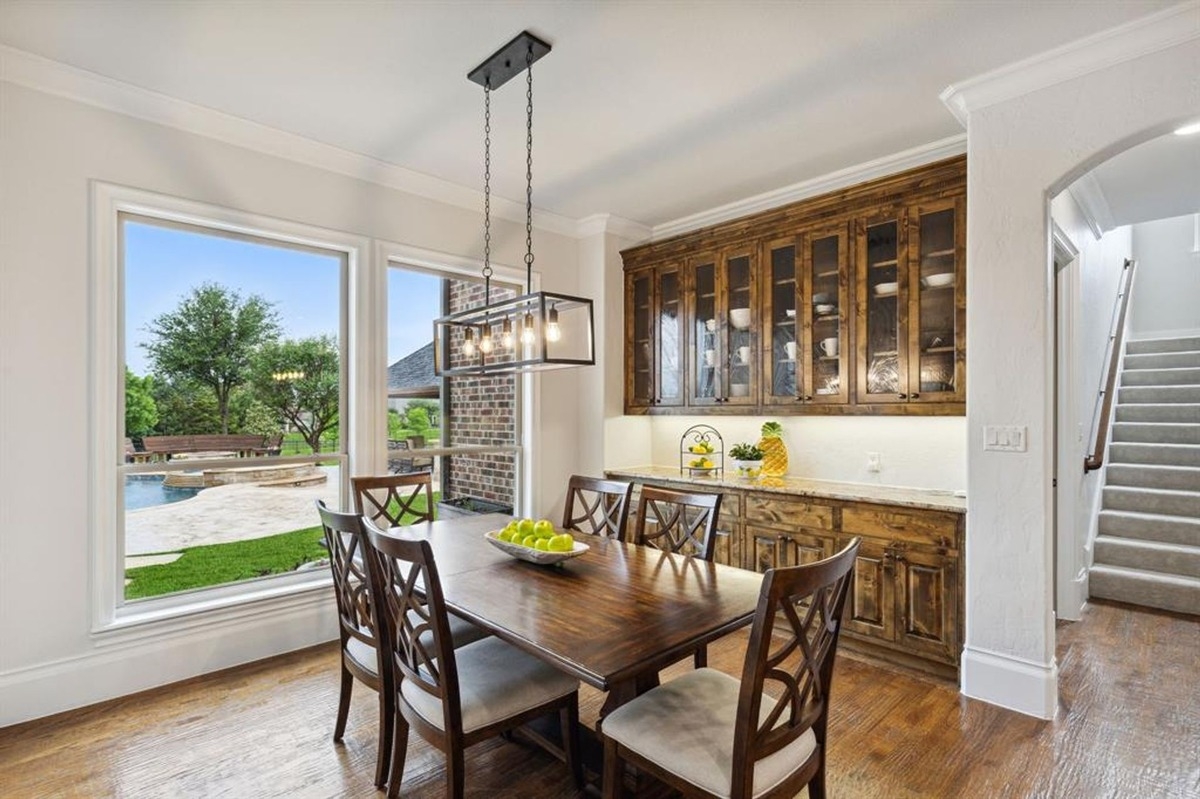 Staircase next to a dining area with a view of the backyard and a swimming pool through large windows.