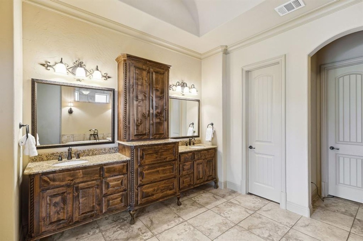 Bathroom featuring dual wooden vanities, granite countertops, and framed mirrors.