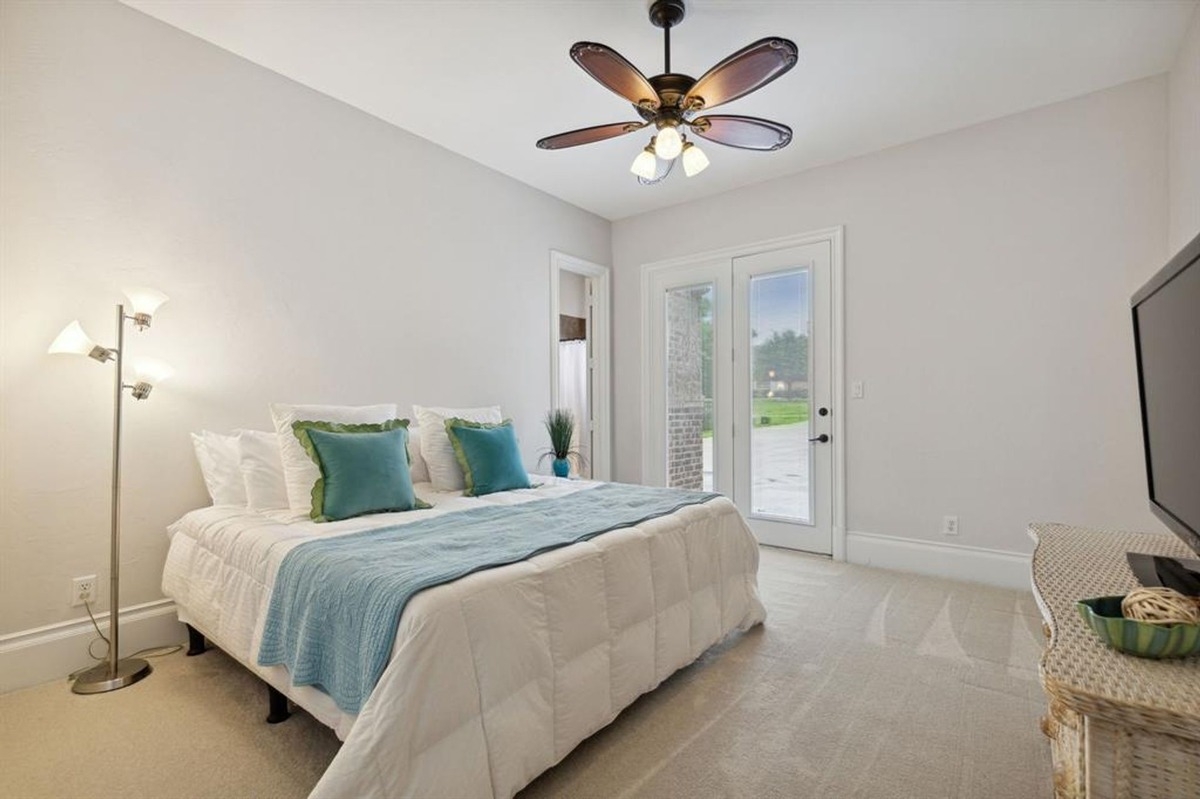 Guest bedroom with a ceiling fan, direct access to the backyard, and white and teal accents.