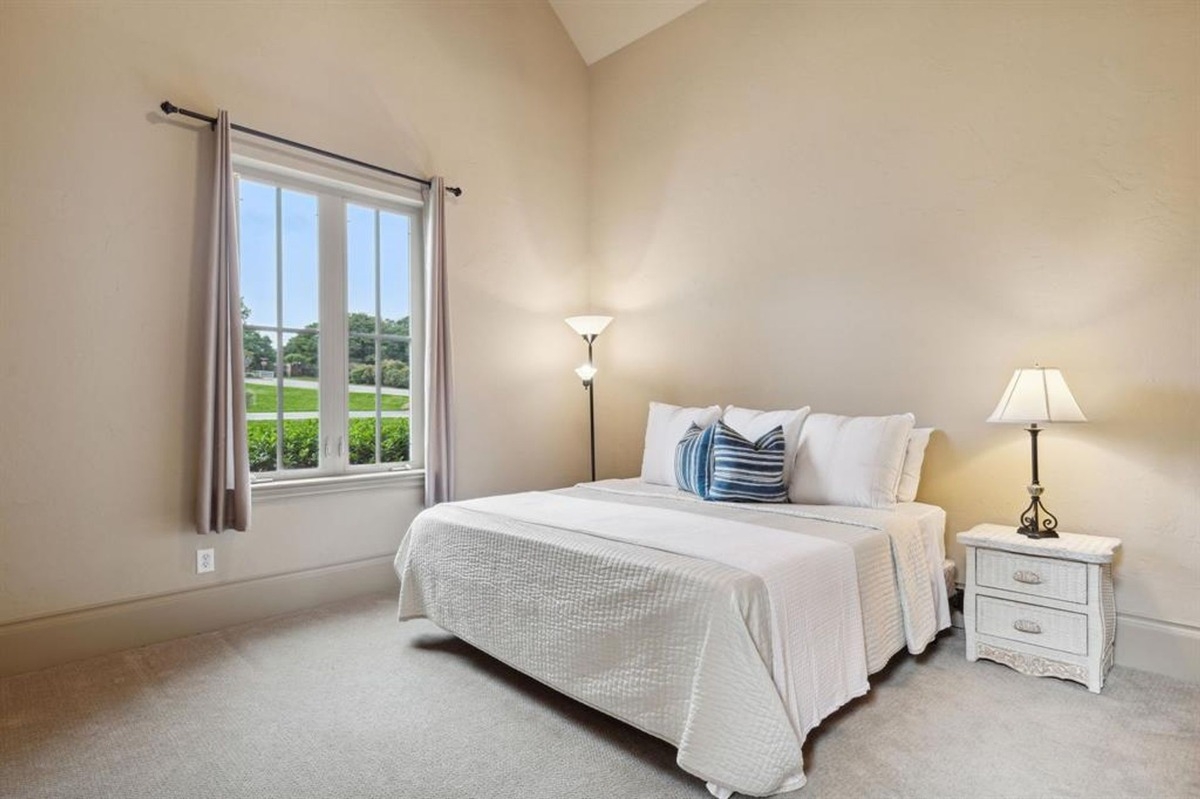 Bedroom with vaulted ceiling, large window, and minimalist furniture arrangement.