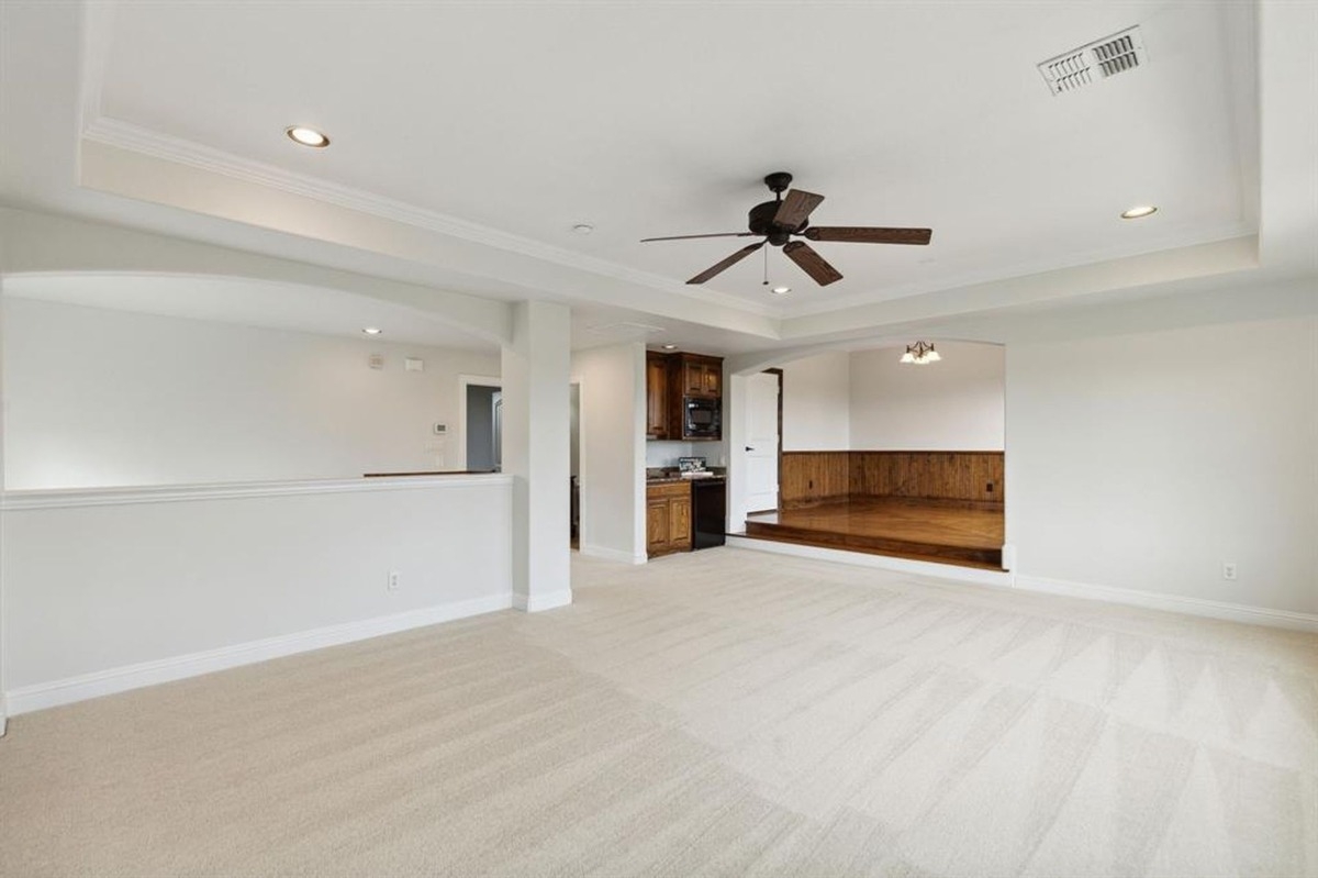 Open upstairs space with carpeted flooring, wet bar, and recessed lighting.