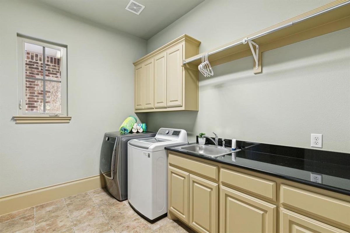 Laundry room featuring a washer, dryer, utility sink, and ample cabinet storage.