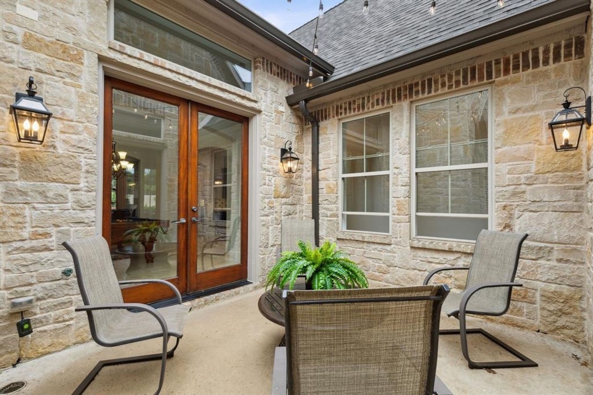 Outdoor seating area with glass-paneled doors and lantern-style lighting fixtures.