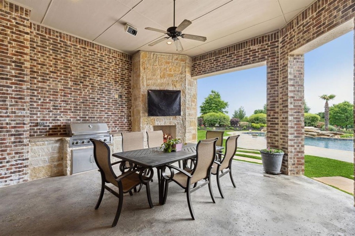 Covered patio with a dining table, built-in grill, and fireplace.