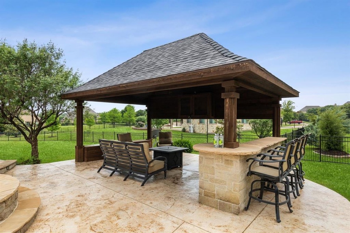 Pavilion featuring a bar, seating area, and neatly landscaped surroundings.