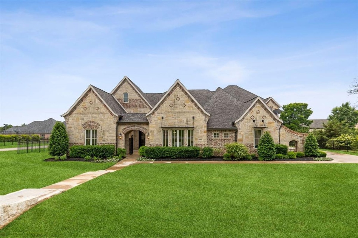 Front view of the house under daytime lighting, highlighting a well-manicured lawn and architectural details.