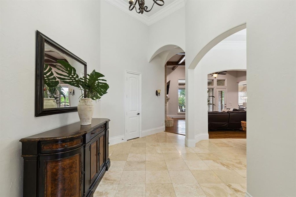 Entryway with tiled floors, an arched doorway, and a dark wood console with a decorative mirror.