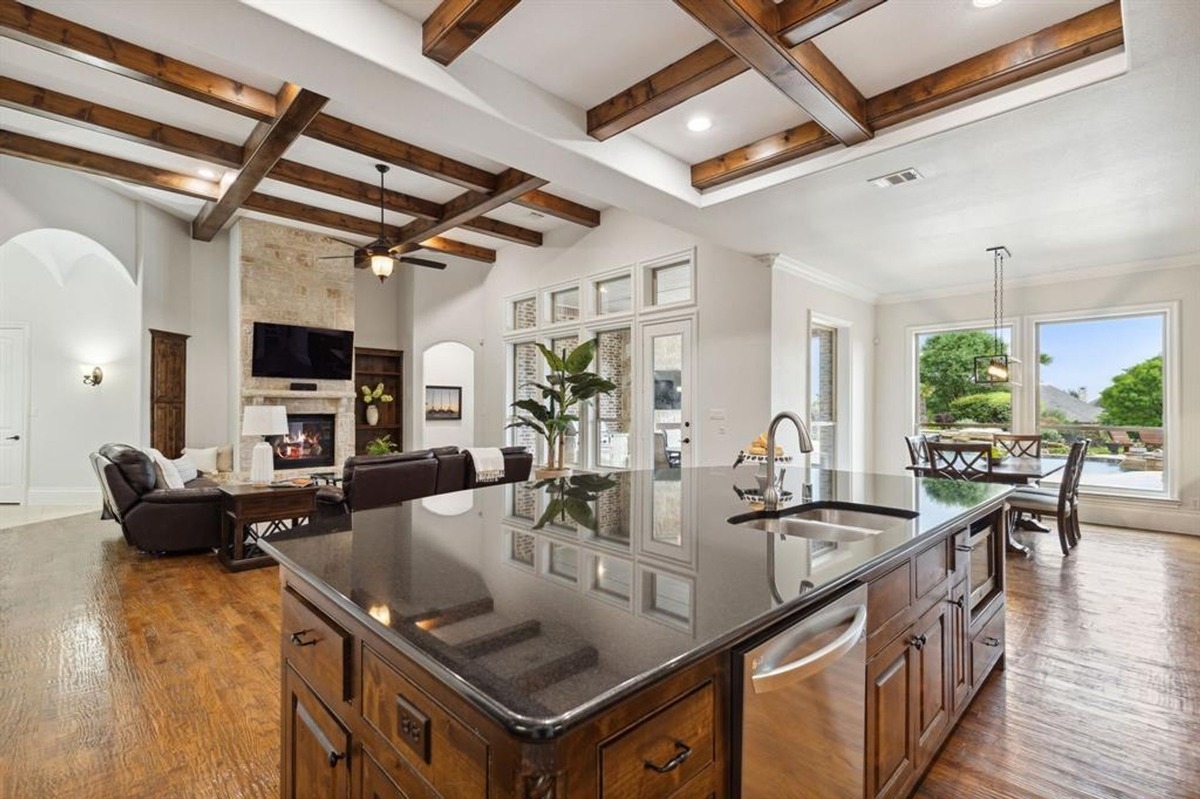 Kitchen and living area viewed from an island with a black countertop and wooden cabinetry.