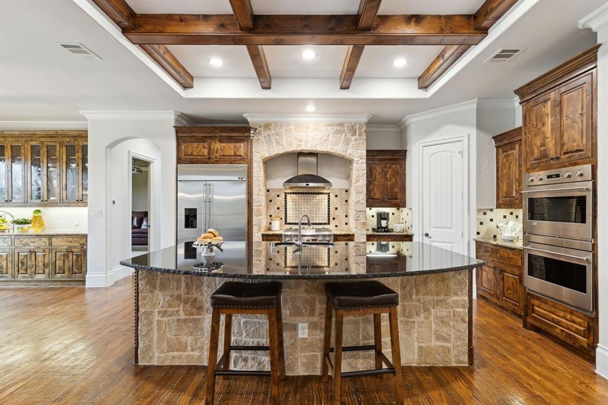 Kitchen with stainless steel appliances, an arched stone cooking area, and dark wooden cabinets.