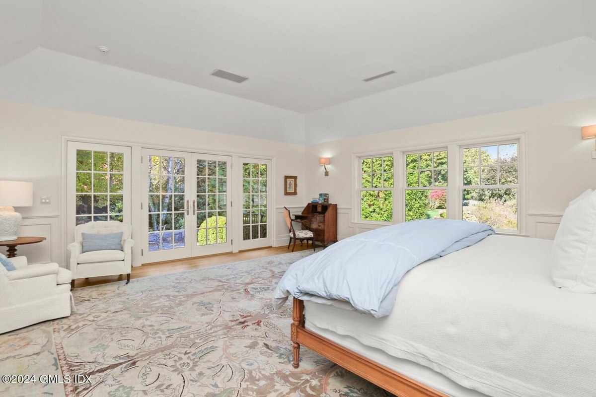 Bedroom has a large bed, French doors, and a patterned rug.