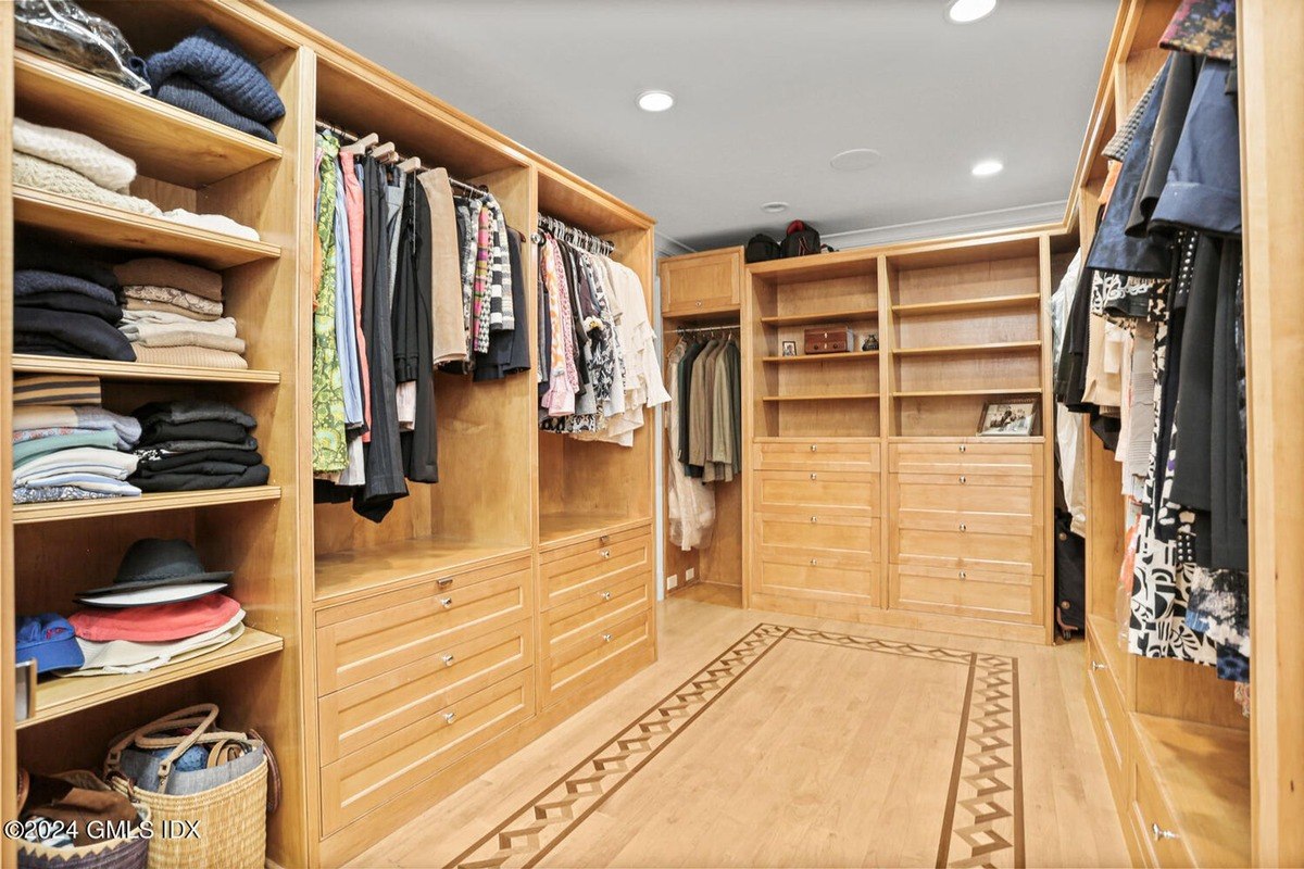 Walk-in closet has wood shelving, drawers, and clothing.