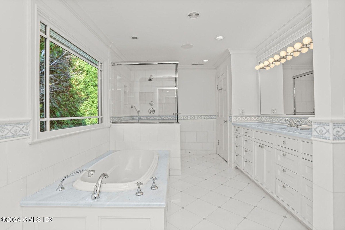 Bathroom has white tile, a bathtub, and a shower.