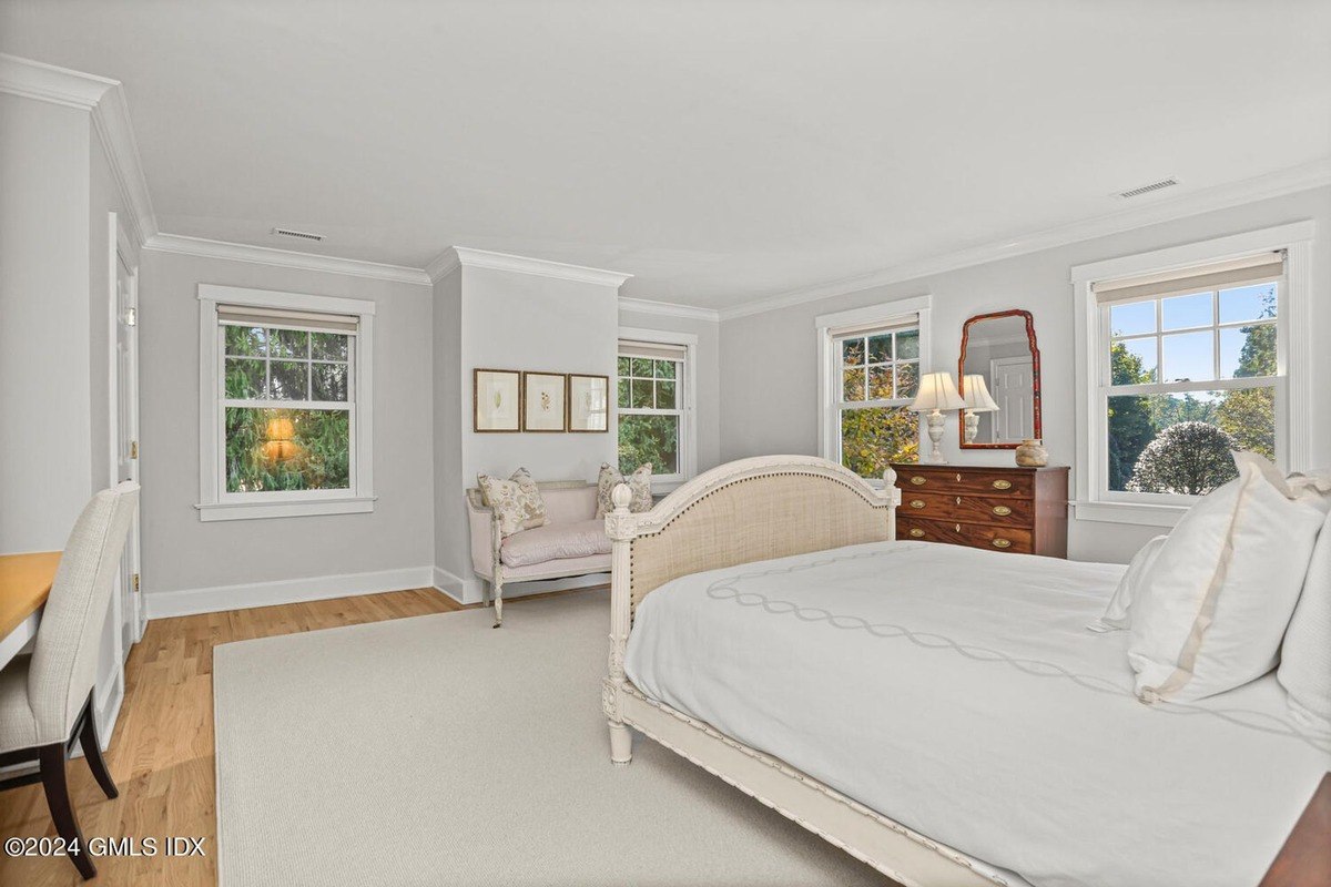 Bedroom has a large bed, light walls, and hardwood floors.