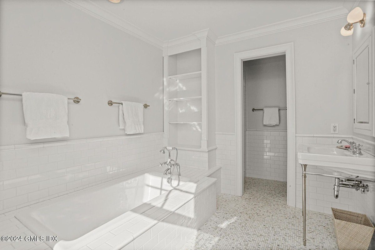 Bathroom has white subway tile, a bathtub, and a pedestal sink.