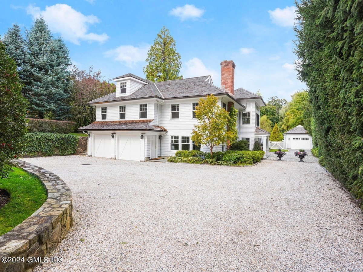 White house has a two-car garage and a gravel driveway.