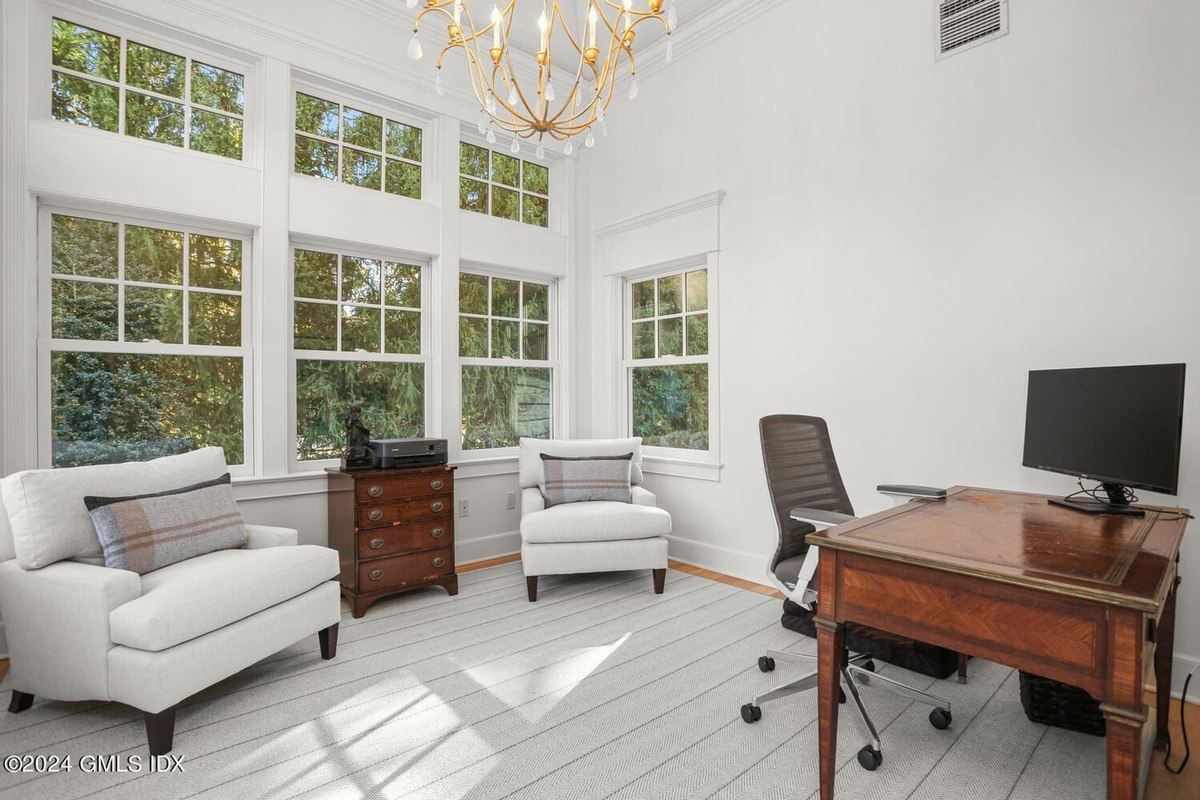 Office has a large window, white chairs, and a wooden desk.