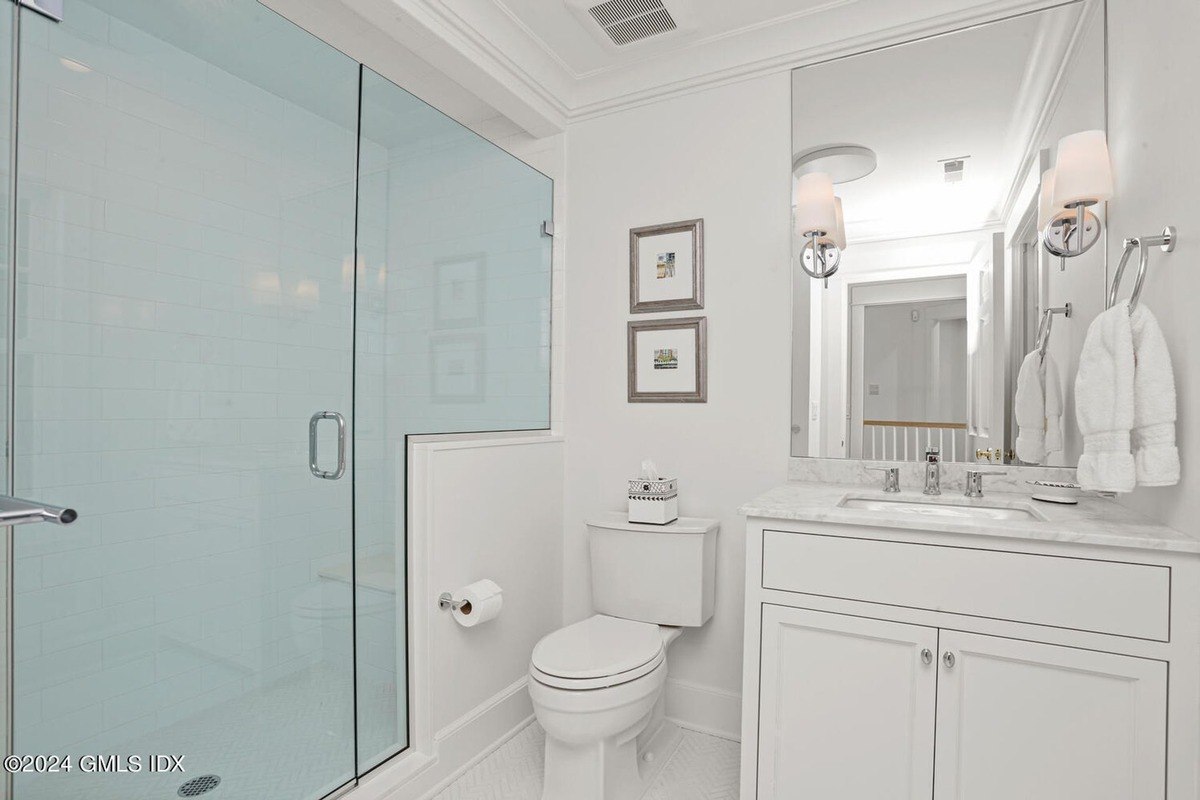 Bathroom has white tile, a glass shower, and a white vanity.