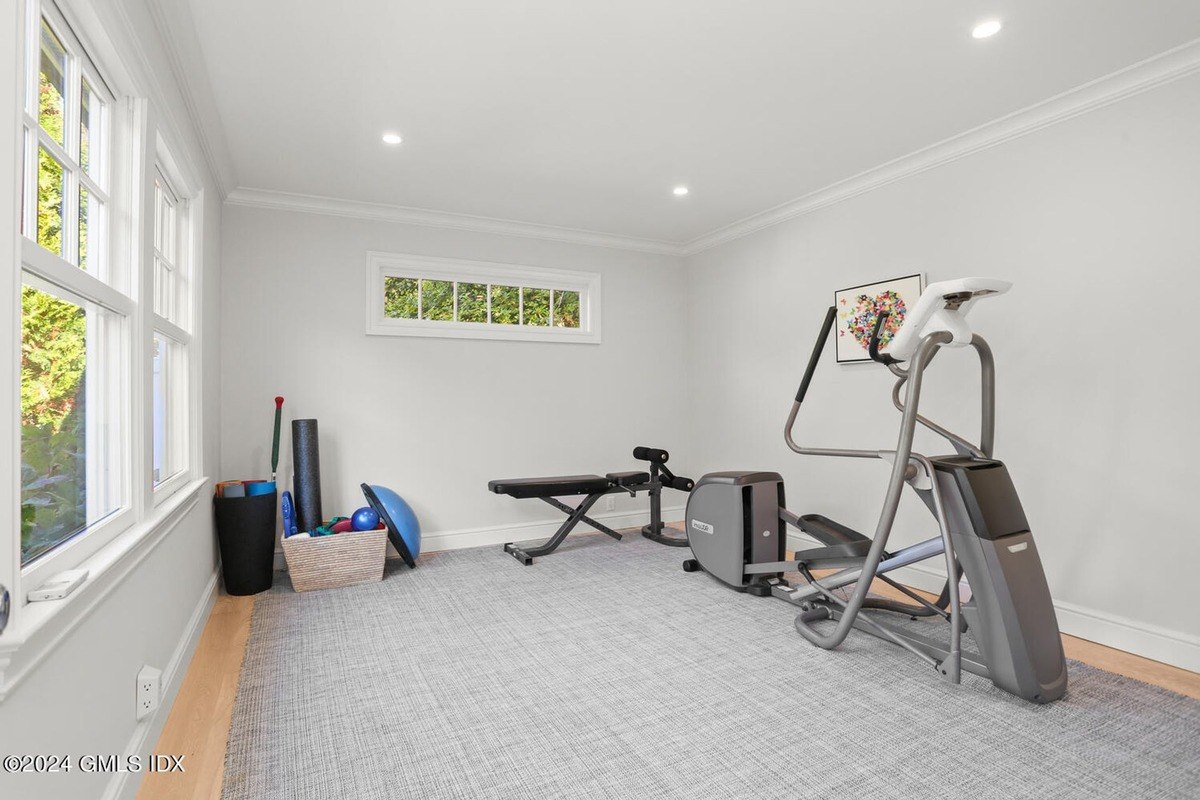 Home gym has an elliptical machine, weight bench, and exercise equipment.