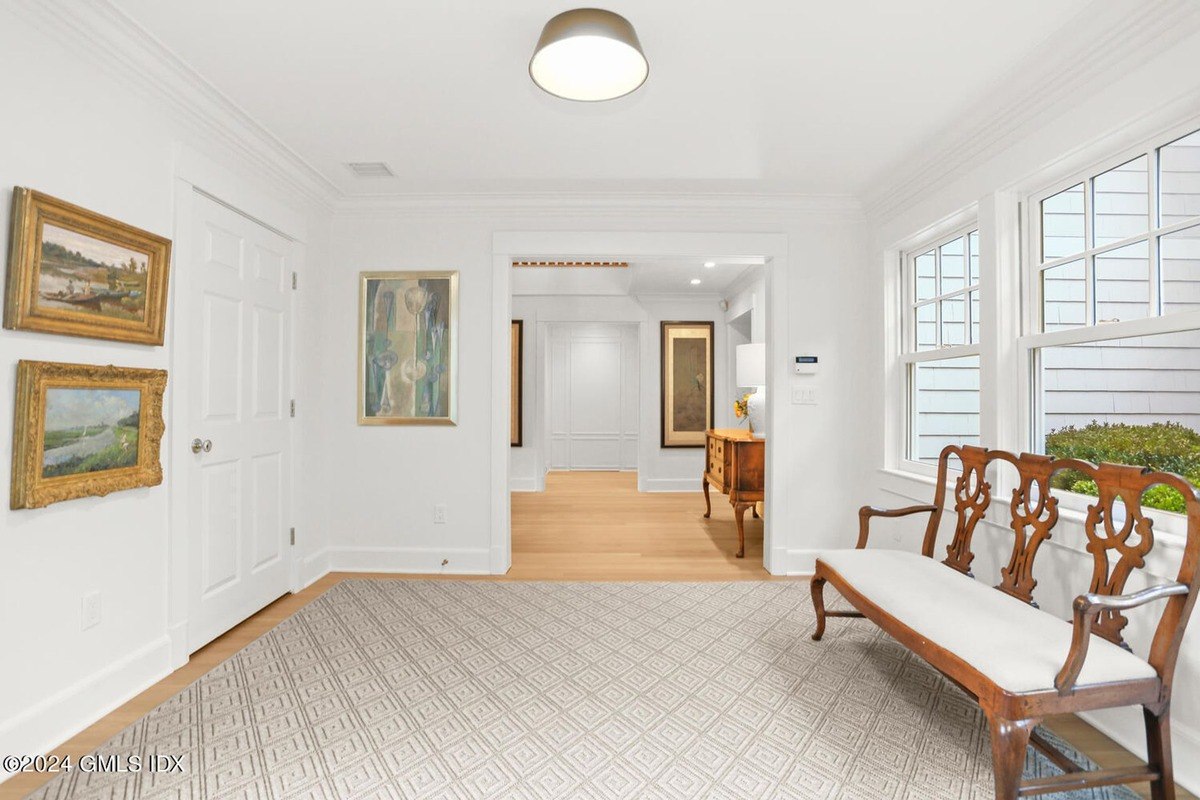 Entryway has white walls, patterned rug, and antique bench.