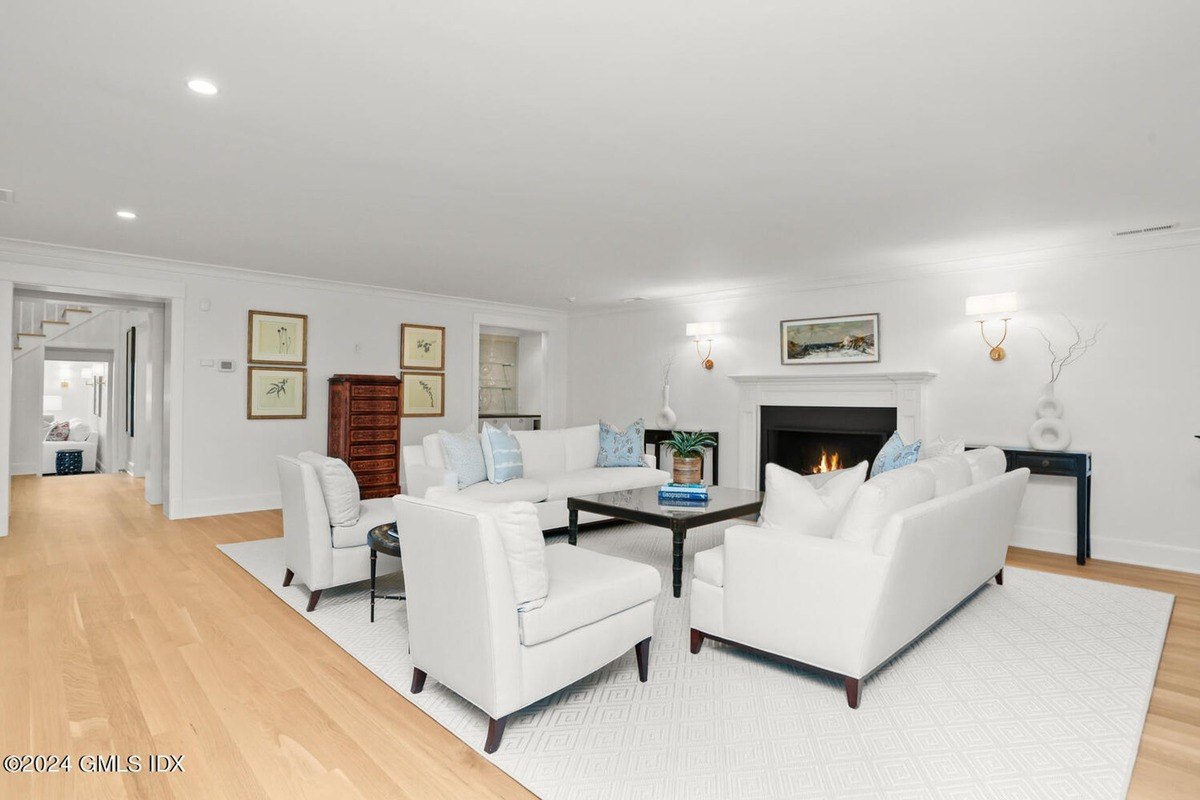 Living room has white sofas, a fireplace, and hardwood floors.