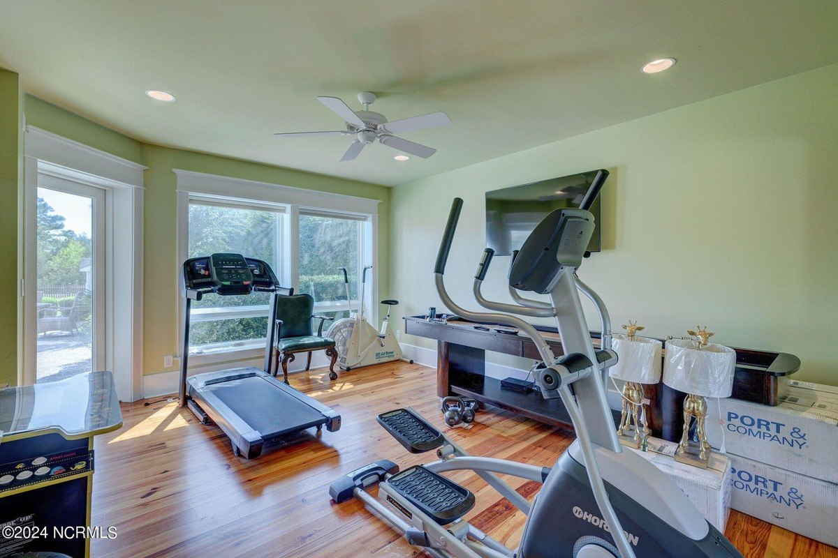 Room has hardwood floors, exercise equipment, and TV.