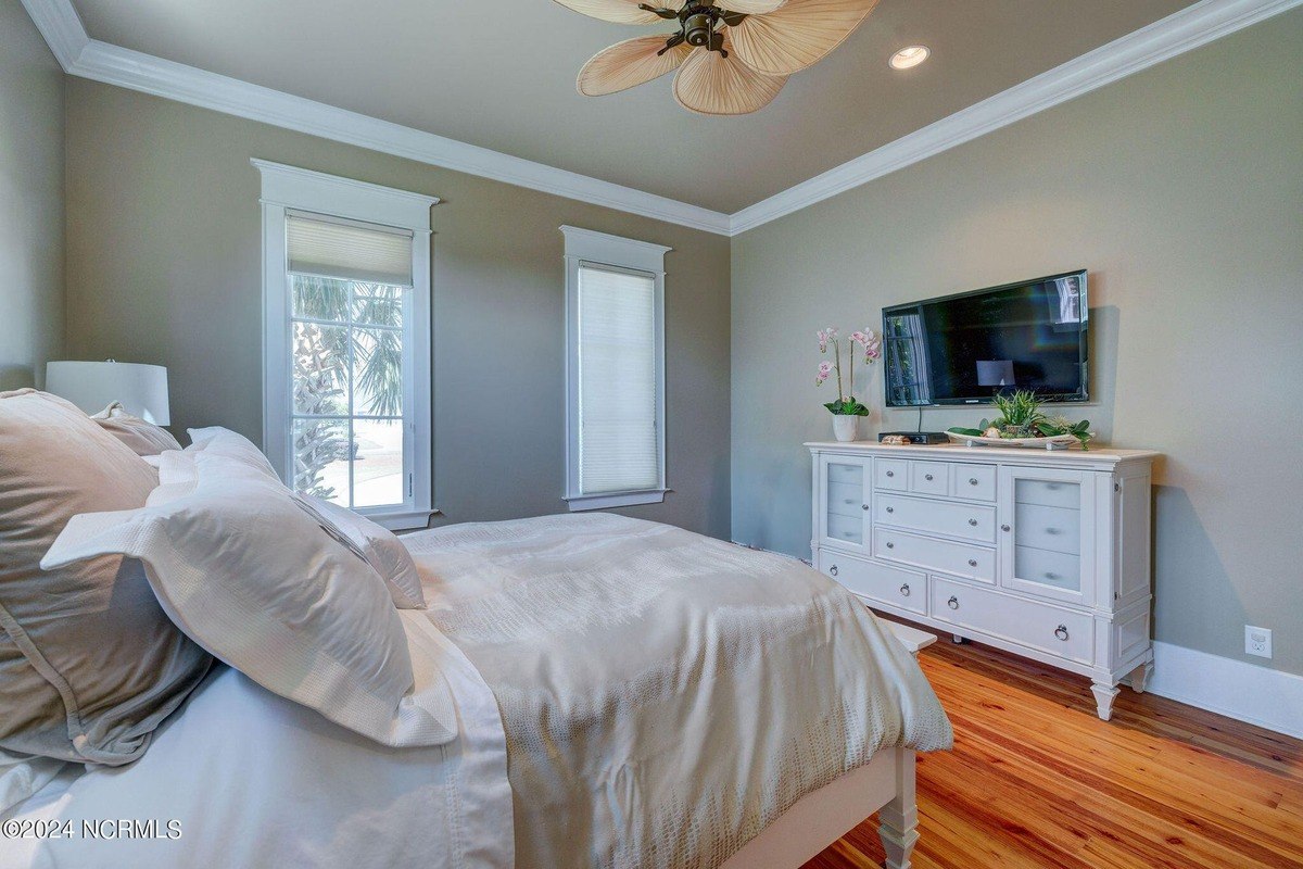 Bedroom has hardwood floors, ceiling fan, and bed.