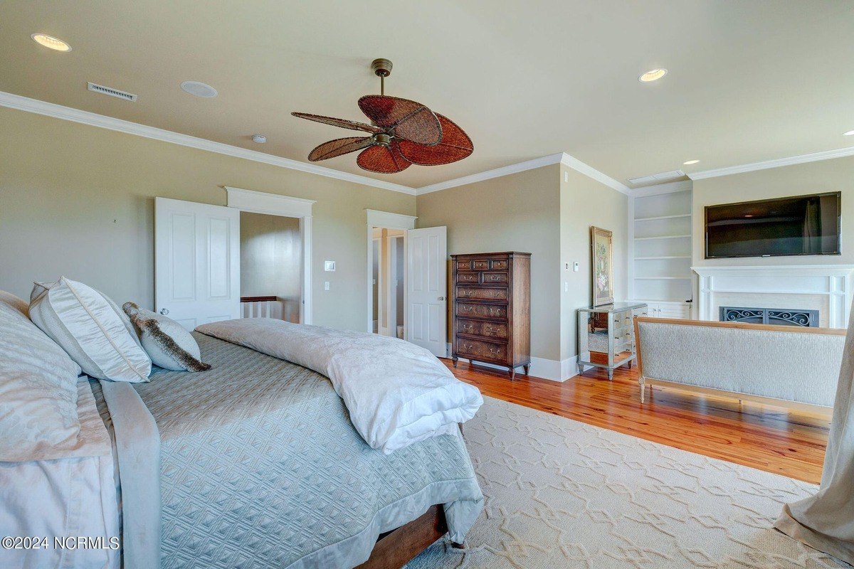 Master bedroom has hardwood floors, ceiling fan, and bed.